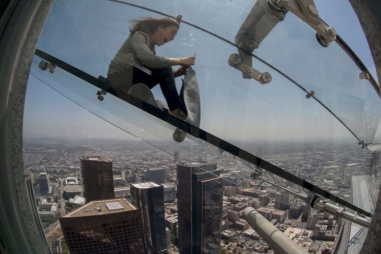 A woman slides down the Skyslide, a 45-foot outdoor glass slide 70 floors up on the outside of the US Bank Tower, on June 23, 2016 in Los Angeles, California, during a preview the opening of the attraction. / AFP PHOTO / DAVID MCNEW