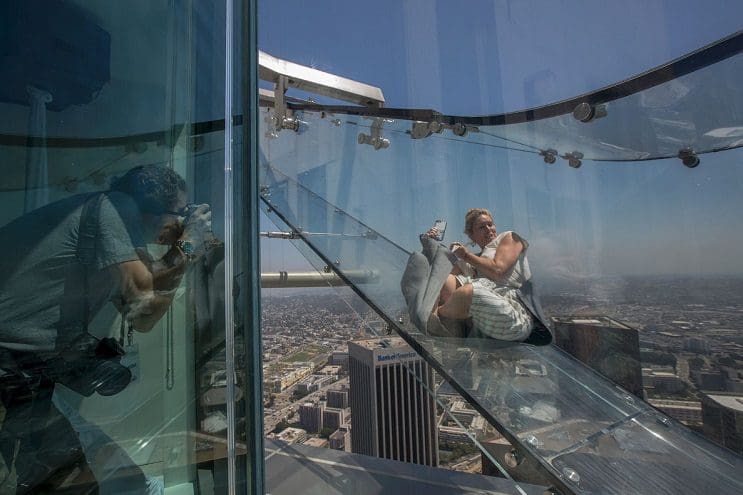 People slide down the Skyslide, a 45-foot (13.7-meter) glass slide 70 floors up on the outside of the US Bank Tower, on June 23, 2016 in Los Angeles, California, during a preview the opening of the attraction.  / AFP PHOTO / DAVID MCNEW