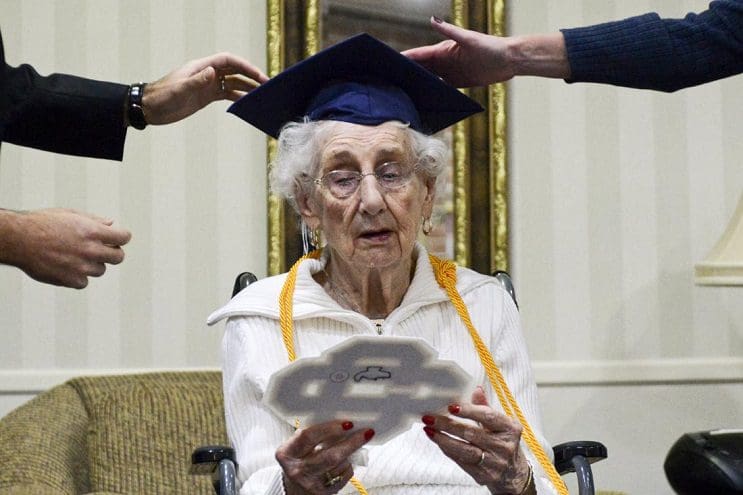 97-year-old Margaret Thome Bekema looks at her high school letter as Catholic Central High School principal Greg Deja, left, and Director of Advancement Beth Banta fix her cap shortly after her honorary graduation at Stonebridge Manor on Thursday, Oct. 29, 2015 in Grand Rapids, Mich.. Bekema began her education at Catholic Central in 1932 but sacrificed completing her degree at that time to take care of her mother who had cancer and her younger siblings. (Emily Rose Bennett/The Grand Rapids Press via AP) ALL LOCAL TELEVISION OUT; LOCAL TELEVISION INTERNET OUT; MANDATORY CREDIT (Emily Rose Bennett | MLive.com)